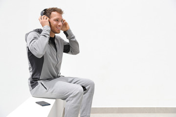 Man listening to music mobile phone app wearing headphones sitting at home. Healthy lifestyle sport athlete using smartphone on jogging break outdoor.