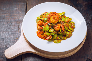 Thai food on white plate and wooden table, Spicy stir-fried shrimp with bitter or twisted cluster or stink bean ( sataw ) and shrimp paste