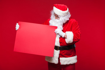 Santa Claus pointing in blank advertisement banner isolated on red background with copy space red leaf