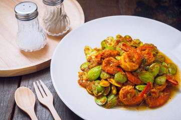 Thai food on white plate and wooden table, Spicy stir-fried shrimp with bitter or twisted cluster or stink bean ( sataw ) and shrimp paste