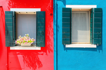 Picturesque windows with shutters on red and blue wall on the famous island Burano, Venice, Italy
