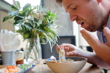 Caucasian man feel surprise with how spicy noodle in soup is.