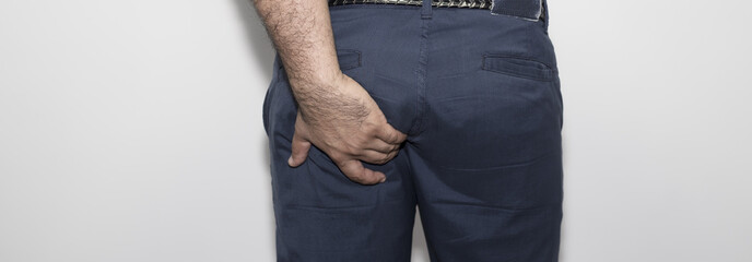 Man with hemorrhoids holding his ass in pain