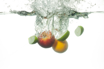 Fototapeta na wymiar Fresh fruits falling into water with splashes