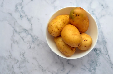 Potatoes in white bowl isolated on white marble background