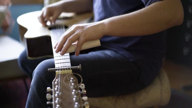 Shallow depth of field with focus on slider of six string slide guitar.