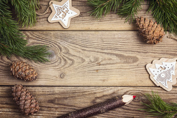 Frame made of pine branches, decorations and pensil on old wooden board. Copy space.