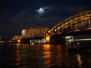 Deutzer Brücke in Köln bei Nacht mit verschwommenen Lichtern und Mond im Hintergrund