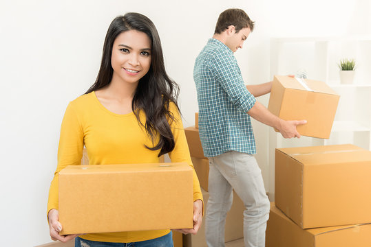 Smiling beautiful Asian woman with her partner moving stuff into new house