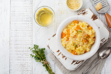 Pumpkin risotto with thyme, garlic, parmesan cheese and white wine on light wooden background. Selective focus. Rustic style. Top view. © kasia2003