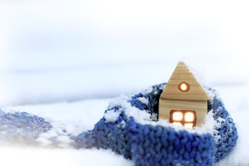 warming technology for winter/ wooden house wrapped in a blue scarf in the middle of snowdrifts
