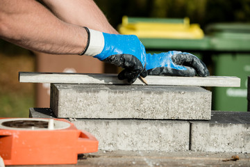 Builder marking a paving stone or block to cut