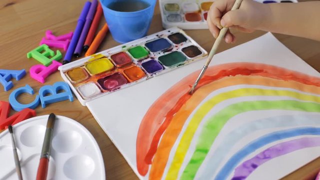 Watercolor painting. Young girl painting a rainbow