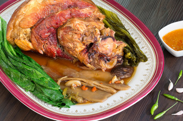 Stewed pork leg with Chinese spices in white dish on wooden background