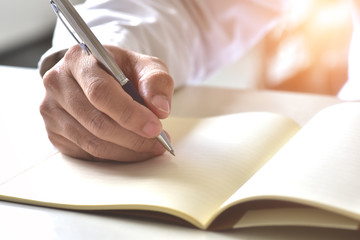 Close up hand writing in an agenda on a desk at home or office