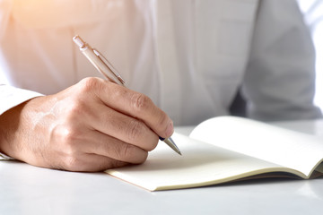 Close up hand writing in an agenda on a desk at home or office