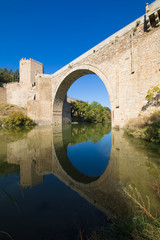 Fototapeta na wymiar arch of Alcantara bridge, landmark and monument from ancient Roman age, reflected on water of river Tagus, Tajo in Spanish, in Toledo city, Spain, Europe 