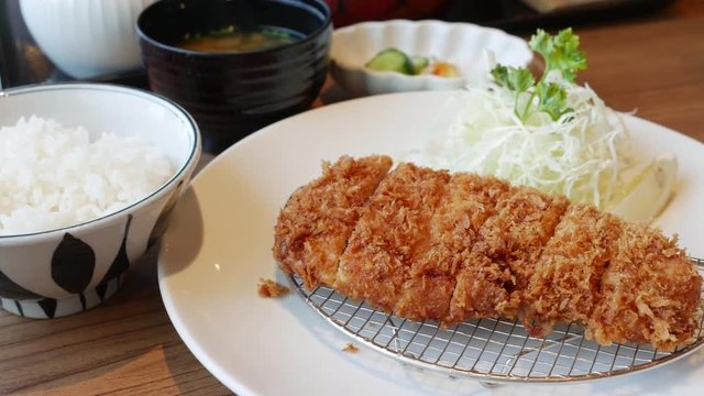 Tonkatsu a Japanese dish which consists of a breaded, deep-fried pork cutlet served with shredded cabbage miso soup and bowl of rice.