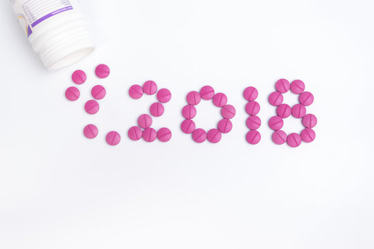 Number 2018 made from pink pharmaceutical  pill, tablets with a bottle.