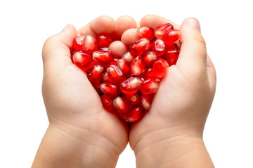 Red heart made of pomegranete seeds in the child hands. Isolated.