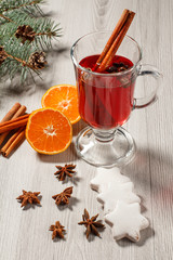 Glass of Christmas mulled wine with spices, orange and cookies on wooden background