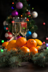 Fototapeta na wymiar traditional New Year's table, tangerines, champagne, Christmas tree and New Year's lights