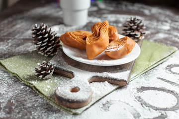 holiday sweets on a New Year's table on a white plate, bumps and a cup of cocoa, a green napkin on a dark background