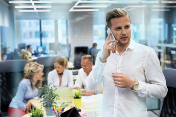 Young man talking on phone in office