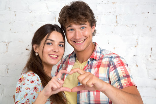 Couple in love gesturing heart with fingers.