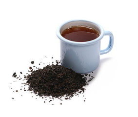 Black tea in blue metal cup and leaves isolated on white background