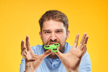 2043240 A young guy with a beard on a yellow background holds a spinner