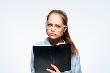 Beautiful young woman on a white isolated background with glasses holding a book