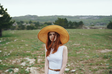 2043250 Beautiful young woman in a hat walking in a field, mountains, nature
