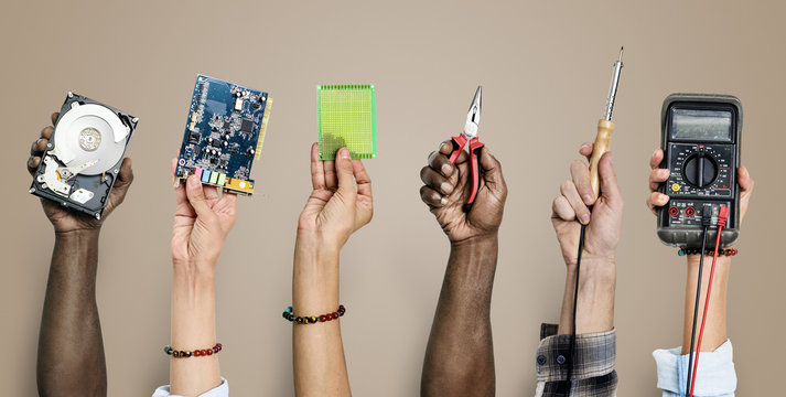 Diverse hands holding electronics tools on brown background