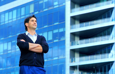 Fototapeta premium Confident happy men entrepreneur enjoying calm after hard work day. Portrait of a young successful business man thinking about something on the background of an office building.