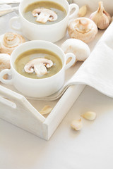 Fototapeta na wymiar Two bowl with traditional mushroom soup cream on white table cloth