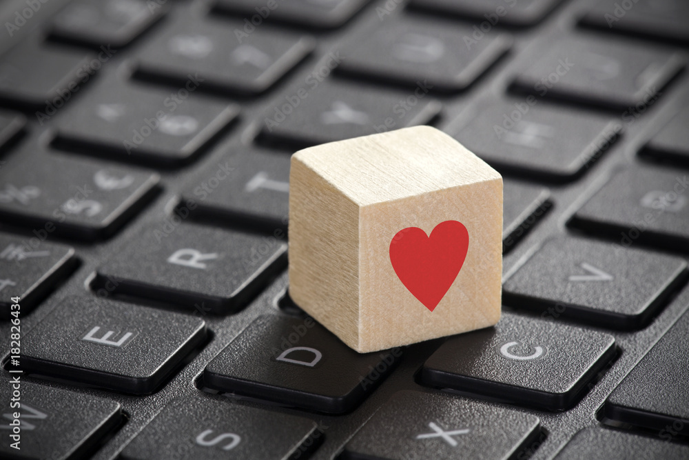 Poster wooden block with red heart shape on laptop keyboard.