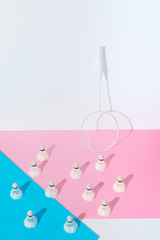 badminton racket and shuttlecocks on blue and pink papers at wall