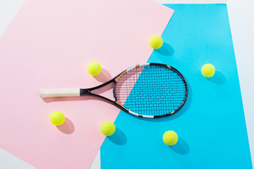 top view of tennis racket and balls on blue and pink papers