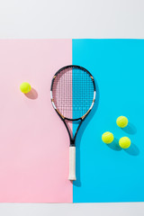 top view of tennis racket and yellow balls on blue and pink papers