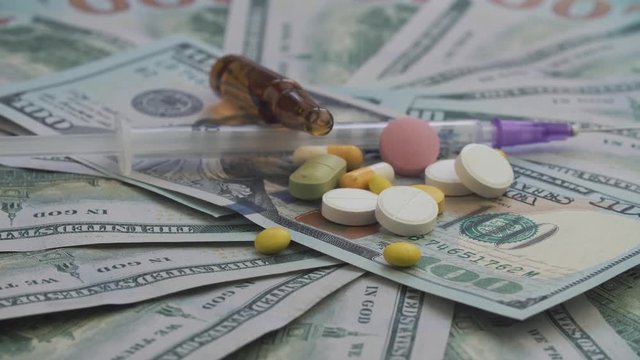 Drugs and pills for addiction lie on the thousands of paper dollars. The frame rotates counterclockwise.