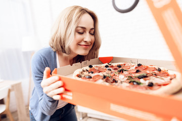 The girl ordered the delivery of pizza at home. A young woman is happy with the delivery of pizza.