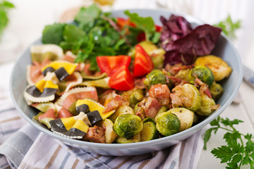 Bowl with Farfalle pasta, Brussels sprouts with bacon and fresh vegetable salad
