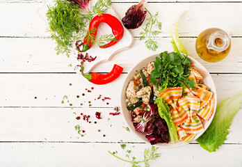 Proper nutrition. Dietary salad. Farfalle pasta durum wheat with baked chicken fillet with eggplant, zucchini and salad in bowl. Top view. Flat lay