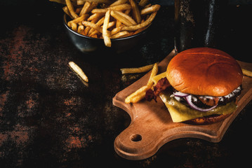 Fresh meat and cheese burger with French fries and glass of dark ginger beer, on dark blue background, copy space