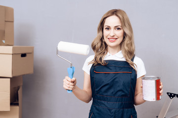 Young woman running a house painter. A woman is engaged in painting the walls.