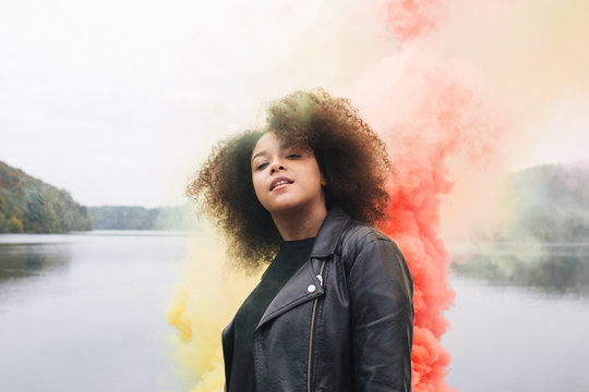 Young woman with colored smoke bombs