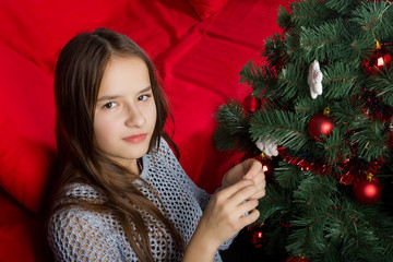 A young girl decorates a Christmas tree at home
