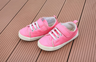 Fototapeta na wymiar Pair of pink baby leather sneakers on wood plank background.