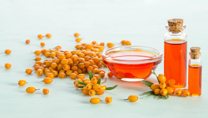 Sea buckthorn and two bottles  with sea buckthorn oil on blue table